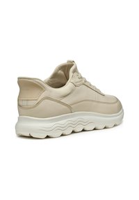 Baskets en cuir beige avec une surface texturée, design à lacets, col rembourré et semelle extérieure blanche, flexible et ondulée. Détail logo subtil sur le talon.