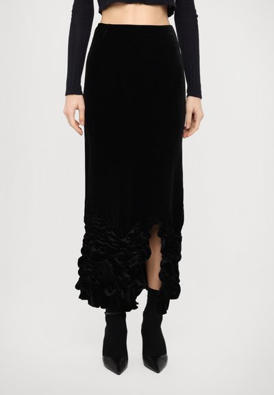 Zwarte fluwelen rok met een gerimpelde zoom en een zijsplit, met een soepele textuur en een tailleringen ontwerp. Gecombineerd met een cropped top en puntige hakken.