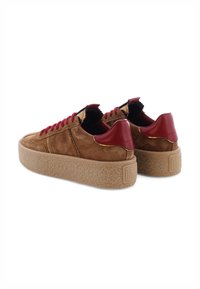 Braune Wildleder-Platform-Sneaker mit dicken, strukturierten Sohlen, roten Leder-Hackenelementen und roten Schnürsenkeln, von hinten und von der Seite betrachtet.