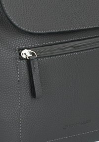 Zwarte textured leren tas met een magnetische klep en een zilverkleurige ritszak. Voorzien van contrasterende stiksels en een klein logo in reliëf aan de voorkant.