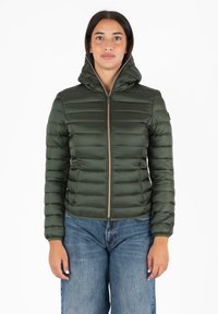 Groene pufferjack met een hoge kraag, rits aan de voorkant en een gestikt ontwerp. Draagt met blauwe wijde jeans. Soepele, glanzende textuur.