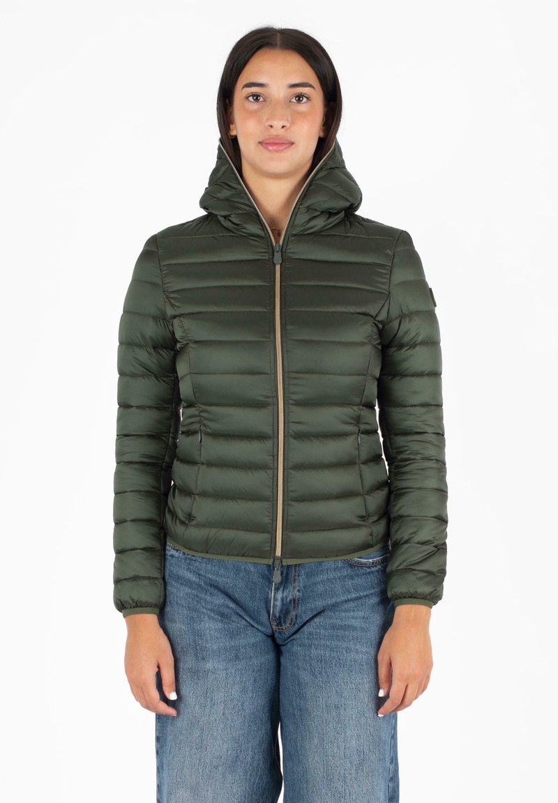 Groene pufferjack met een hoge kraag, rits aan de voorkant en een gestikt ontwerp. Draagt met blauwe wijde jeans. Soepele, glanzende textuur.