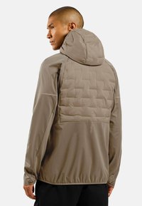 Light brown jacket with a quilted padded back and hood. Features elastic hem and textured fabric. No visible fasteners or patterns.