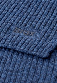 Tessuto a maglia blu rigato con superficie testurizzata; presenta un piccolo logo ricamato in filo scuro al centro.