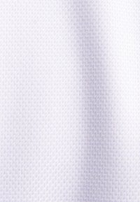 Tessuto bianco con una texture a spina di pesce. Il materiale appare leggero e liscio, riflettendo la luce in modo sottile sulla superficie.