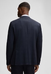 Marineblauwe gestreepte colbert gezien vanaf de achterkant, met een notch lapel, twee achterventilaties en drie knopen op elke manchet. Gladde textuur.