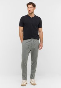 Sort kortærmet henley skjorte med tre knapper, kombineret med lysegrå bukser med snørreland, der har et struktureret mønster og en taperet pasform.