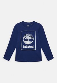 Námořnické tričko s dlouhým rukávem z bavlny, s bílým logem stromu a textem "Timberland" v obdélníkovém rámečku. Kulatý výstřih.