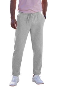 Graue Sweatpants aus einem weichen Material, ausgestattet mit einem elastischen Taillenbund und einem Kordelzug, sowie mit Bündchen an den Säumen, kombiniert mit weißen Sneakers.