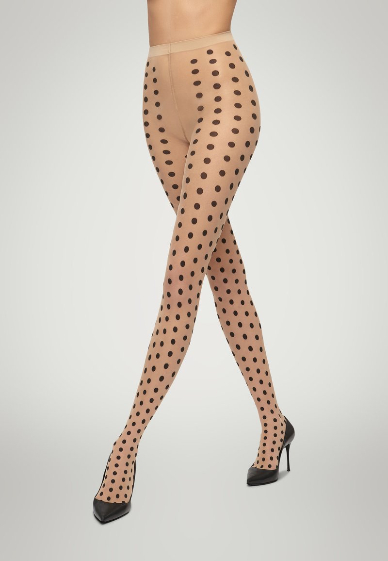 Collant a pois nudi con pois neri, caratterizzati da una texture liscia e una vita comoda, abbinati a tacchi alti neri.