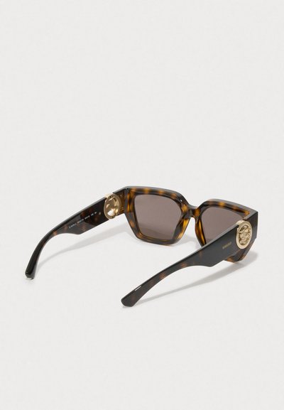 Occhiali da sole tartarugati con lenti esagonali, vetro oscurato marrone e dettagli in metallo color oro sulle astine presentano un design distintivo.