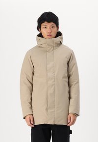 Parka impermeabil bej cu guler înalt și glugă, având o croială dreaptă, mâneci lungi și un design minimalist. Potrivit pentru vreme rece.
