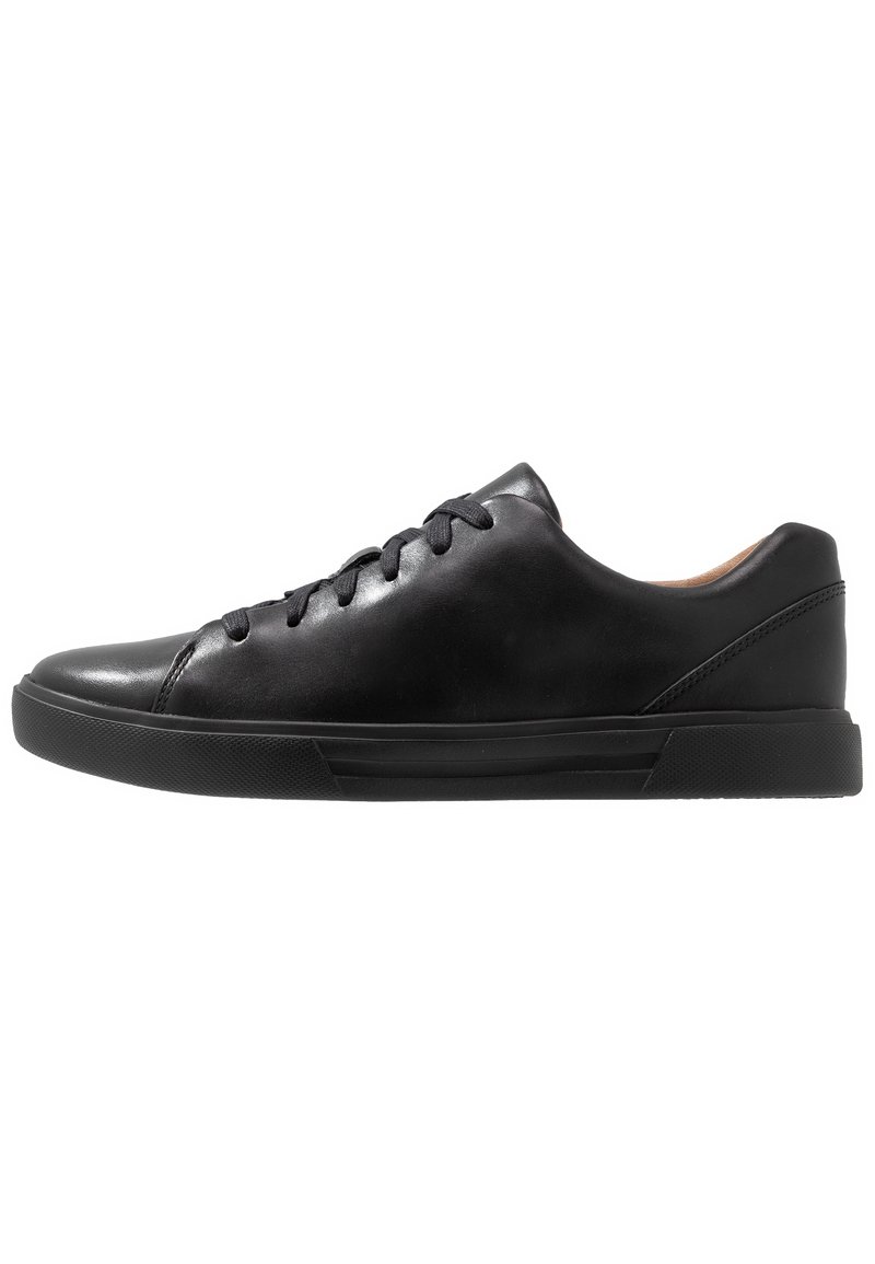 Baskets basses en cuir noir avec lacets noirs, semelle en caoutchouc et détails cousus sur fond blanc, vues de côté gauche.