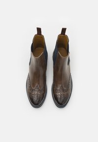 Botas de tornozelo em couro castanho com um acabamento suave, bico texturizado em padrão crocodilo, painéis laterais elásticos azuis e puxador castanho.
