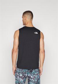 Μαύρο αμάνικο πουκάμισο από ελαφρύ ύφασμα. Διαθέτει ένα μικρό λευκό λογότυπο στο πίσω μέρος και έχει χαλαρή εφαρμογή, σε συνδυασμό με μοτίβο βερμούδες.