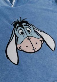 Poncho in pile blu con il volto di Eeyore, caratterizzato da dettagli ricamati e una texture morbida. Include orecchie grandi e un profilo cucito.