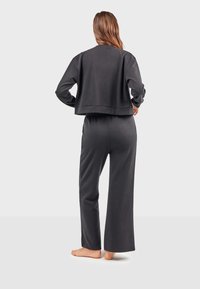 Dunkelgraues Loungewear-Set bestehend aus einem cropped Sweatshirt und weiten Hosen, gefertigt aus weichem Stoff mit lockerer Passform und elastischem Bund.