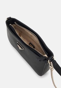 Sort tekstureret håndtaske med guldfarvet hardware, lynlås lukning og flere rum. Indersiden har en lyse beige foret og kortslot.