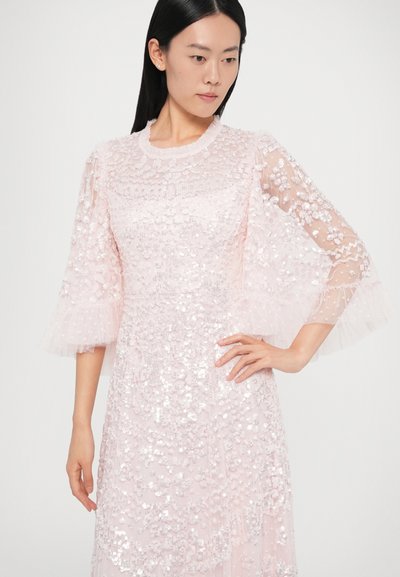 Rochie roz deschis cu mâneci evazate și transparente. Împodobită cu paiete și țesătură texturată. Are un decolteu rotund și un design stratificat.