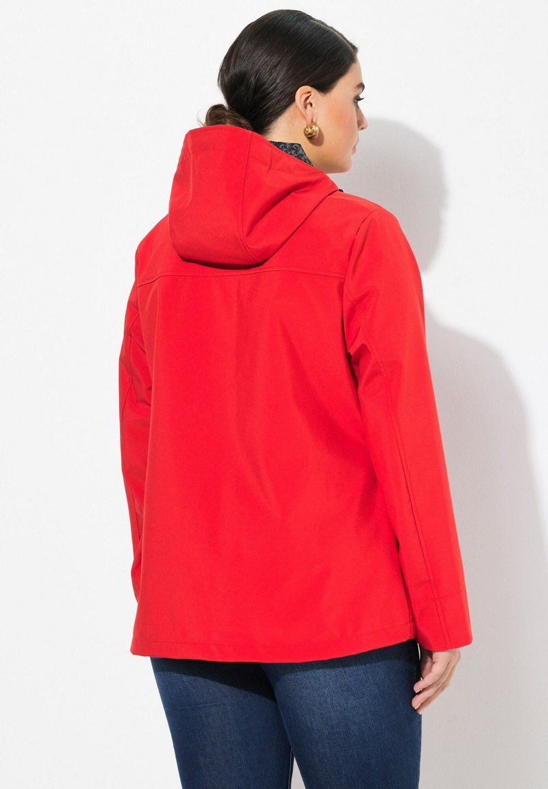 Rode hoodie van glad, waterafstotend materiaal. Heeft een ontspannen pasvorm, lange mouwen en is heup lengte.
