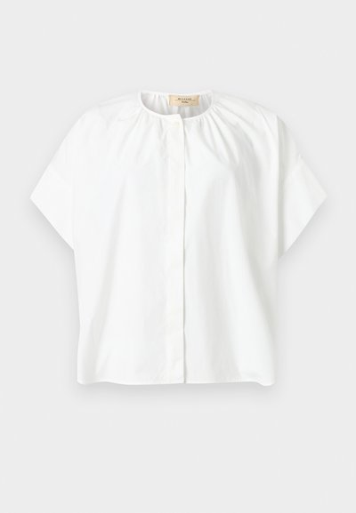 Λευκό μπλουζάκι με κοντά μανίκια και στρογγυλή λαιμόκοψη, με πιέτες κοντά στον γιακά και κρυφά κουμπιά μπροστά.