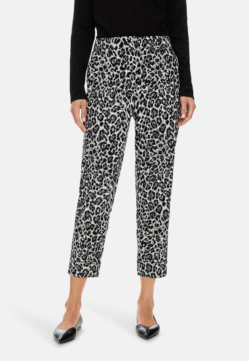 Schwarz-weiße Leopardenmuster-Hose mit lockerer Passform, elastischem Bund und schmal zulaufenden Beinen, kombiniert mit schwarzen spitzen High Heels.