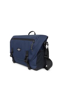 Borsa a tracolla blu navy con tracolla nera regolabile, tasca frontale con zip, chiusure a fibbia e logo Eastpak sulla parte anteriore della patta.