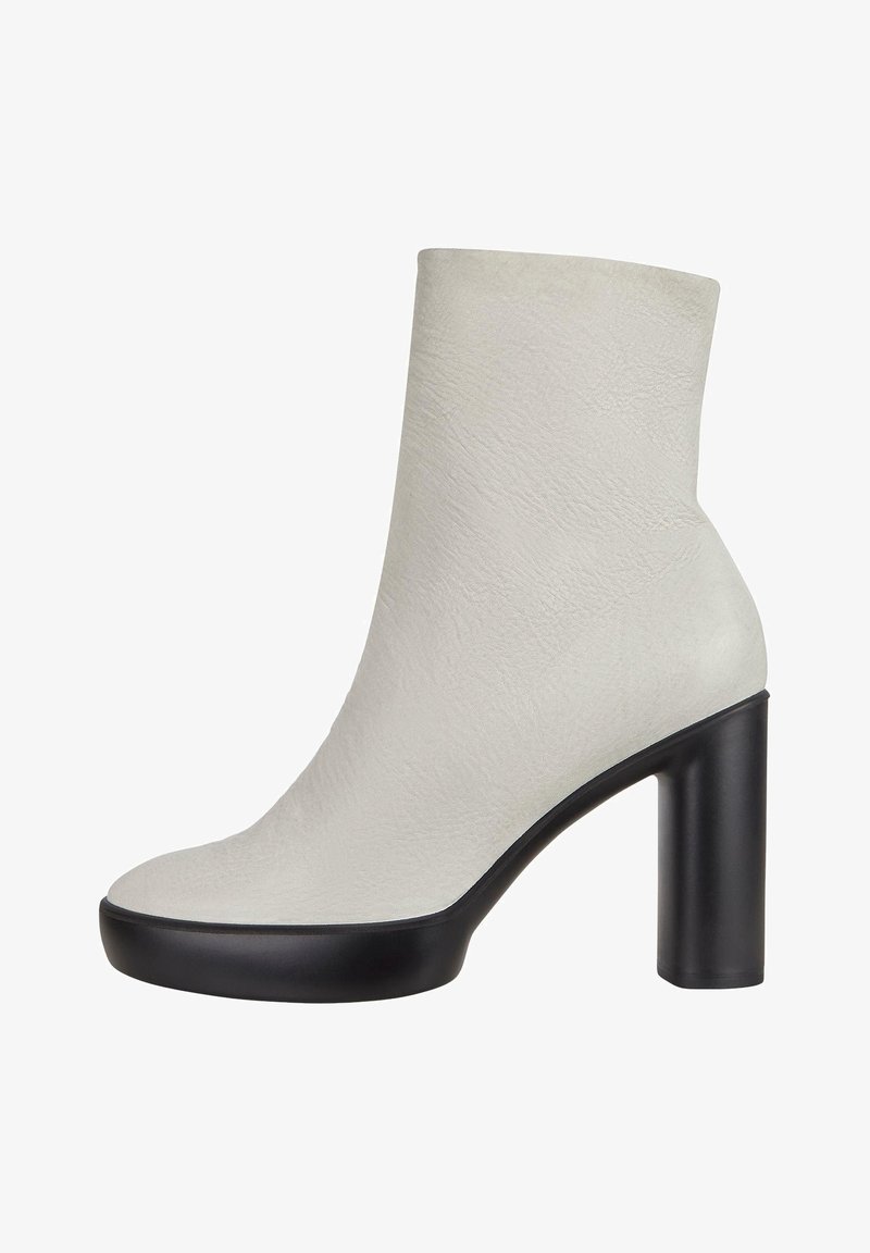 Vita texturerad ankelskänga med rund tå och kraftig svart klack. Slät yta och minimalistisk design. Lämplig för olika tillfällen.