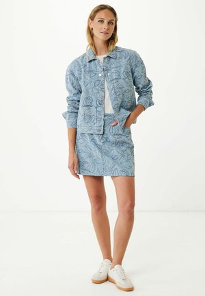 Veste en denim bleu clair avec broderies florales, associée à une jupe en denim brodée assortie. Des baskets blanches complètent la tenue.