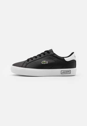Czarne skórzane sneakersy z białą podeszwą, charakteryzujące się czarnymi sznurowadłami, zielonym logo krokodyla oraz białym akcentem na pięcie.