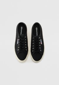 Sneakers neri in tela con suole e occhielli bianchi, dotati di lacci e di un piccolo logo laterale. Design classico a basso profilo.