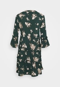 Blommig klänning i mörkgrön tyg, med krämfärgade och rosa blommor, långa ärmar med volangärmar, lagerdesign och rund halsringning.