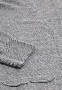 Cardigan grigio lavorato a maglia con texture a costine, scollatura a V e dettagli smerlati sull'orlo. Materiale morbido e caldo con maniche lunghe.