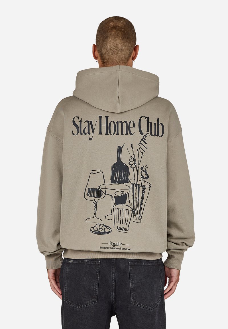 Khaki hettegenser med et svart grafisk design av drikkevarer og planter på baksiden, med ribbestrikkede mansjetter og kant.