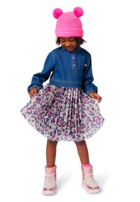 Denim-overdel med knappestolpe og rynkede lange ermer; trykt tylskjørt med rosa og lilla hjerter. Rosa strikket lue med pom-pomer.