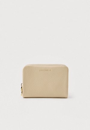 Beige teksturert lærpengebok med gullglidelås og preget merkevare navn "Coccinelle" foran mot hvit bakgrunn.