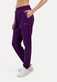Lilla sweatpants i blødt stof, med snøre i taljen, sidelommer og elastiske manchetter. Én accent logo detalje.