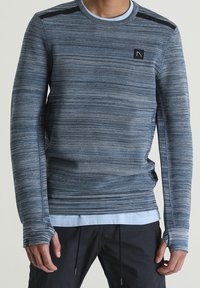 Niebieski długi rękaw sweter z teksturowanym splotem, z czarnym akcentem na ramieniu i otworami na kciuki przy mankietach.