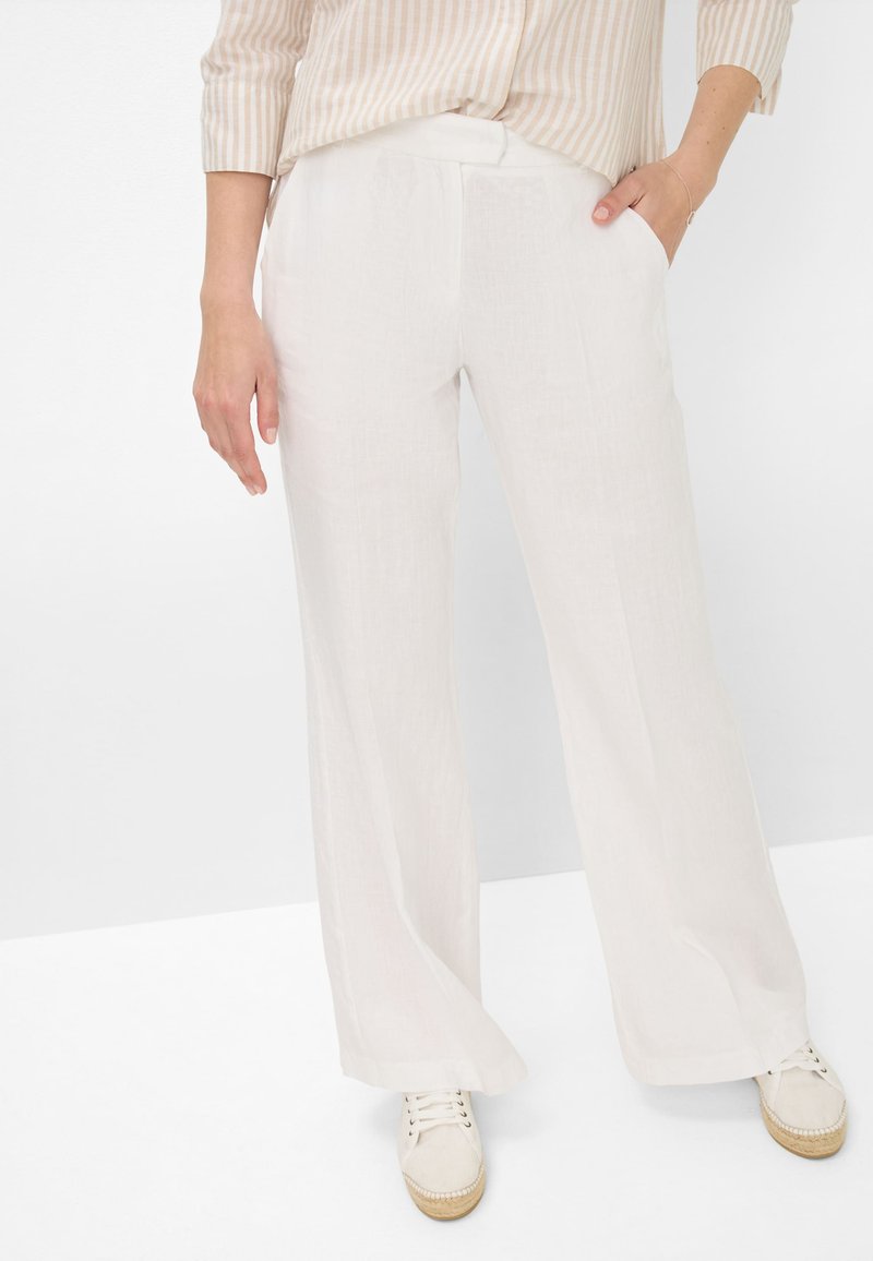 Witte linnen wijde broek met een textuurafwerking, voorzien van zijzakken en een relaxte pasvorm, gedragen met lichtgekleurde casual schoenen.