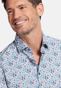 Witte overhemd met knopen, voorzien van een kleurrijk bloemmotief met blauwe, paarse en gele accenten. Zachte stof met een gespreide kraagontwerp.