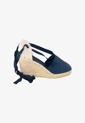 Alpargata cuña azul marino con tacón de yute tejido y tiras para atar al tobillo sobre fondo blanco
