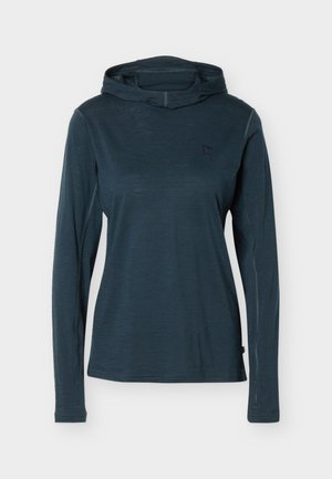 Temno modra majica z dolgimi rokavi in kapuco, s slim fit krojem in majhnim logotipom na levi strani prsnega koša, prikazana na enostavni svetli podlagi.