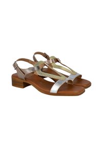 Sandalias metálicas en bronce y plata con tacón plano, que presentan tiras texturizadas y un diseño de punta abierta sobre una suela marrón.