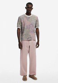 Cămașă cu mâneci scurte, texturată, în nuanțe pastelate, cu un model tricotat cu nervuri, asortată cu pantaloni largi de culoare roz deschis și pantofi slip-on bej.