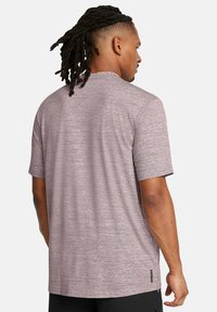 Camiseta atlética de manga corta en color malva claro con un patrón texturizado, que presenta un cuello redondo y un sutil detalle del logo cerca del cuello.