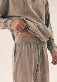 Szara bawełniana bluza i spodnie dresowe. Spodnie mają elastyczny pas ze sznurkiem i boczne kieszenie. Teksturowana tkanina, luźny krój.