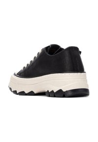 Zapatillas de cuero negras con suela gruesa de color crema. Presentan una suela negra texturizada con grandes surcos y costura lateral. Diseño de cordones.