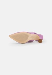 Scarpa con tacco alto in suede rosa, a punta e con suola in gomma. Il tacco è marrone, con una base quadrata, caratterizzata da scanalature texturizzate sulla suola.