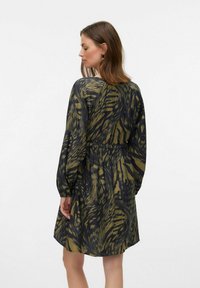 Robe à manches longues en vert olive avec des motifs en tourbillon noirs complexes. Dotée d'une taille élastique et d'une coupe décontractée, elle arrive au-dessus du genou.