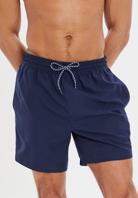 Costumi da bagno nautici con vita elastica, dotati di coulisse con dettagli bianchi e un fit rilassato. Realizzati in tessuto leggero.